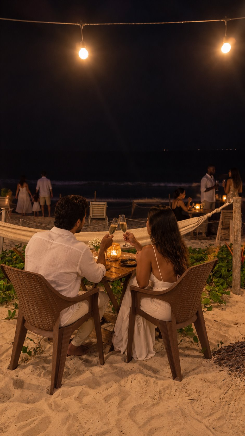 Mesa Beira-Mar na areia, com casal brindando diante do mar